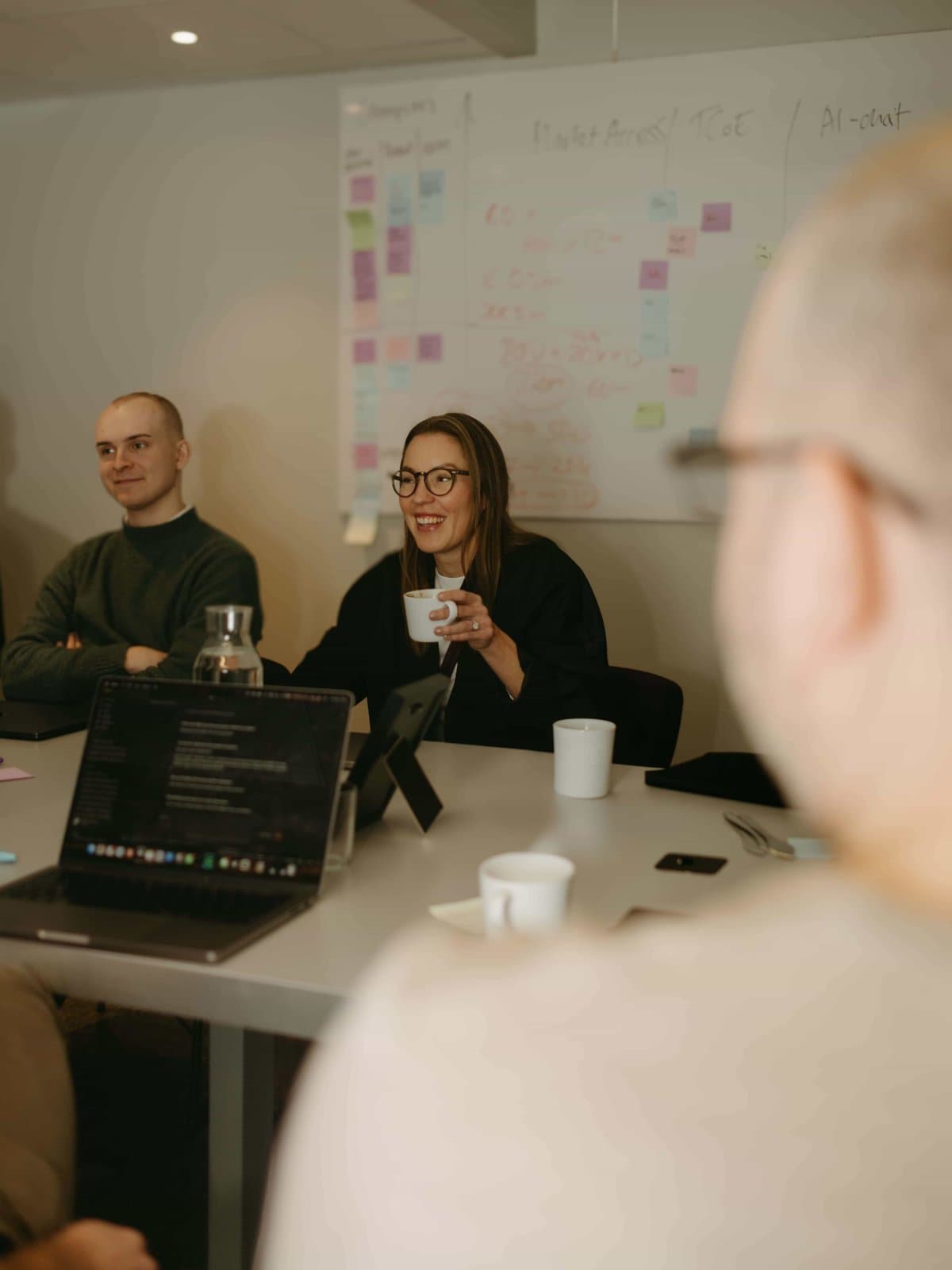 Two of the Engrate team at the meeting-room table on a team day, a whiteboard covered in sticky notes behind them