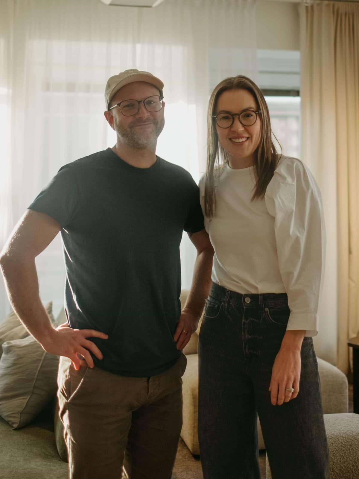 The two Engrate co-founders standing side by side in the office, daylight through the curtains behind them